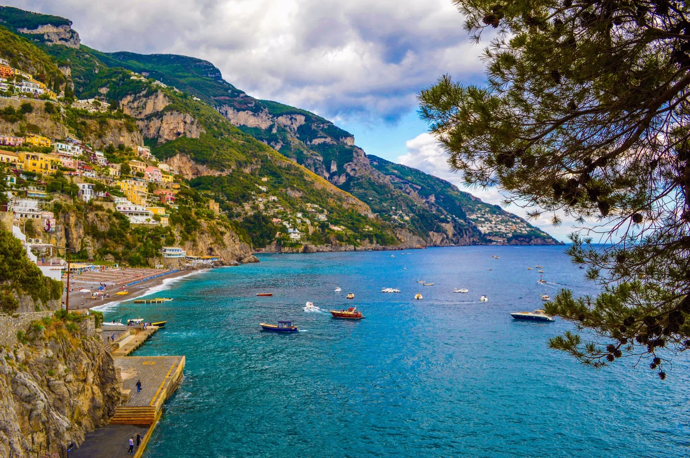 Blue water and boats beneath the cliffside town of Positano, Italy.